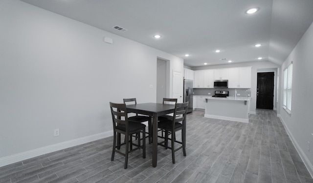 dining space featuring wood-type flooring and lofted ceiling