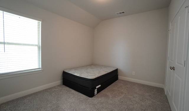 carpeted bedroom featuring multiple windows and lofted ceiling