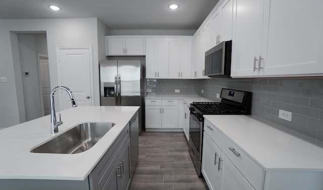 kitchen featuring white cabinetry, sink, dark wood-type flooring, a center island with sink, and appliances with stainless steel finishes