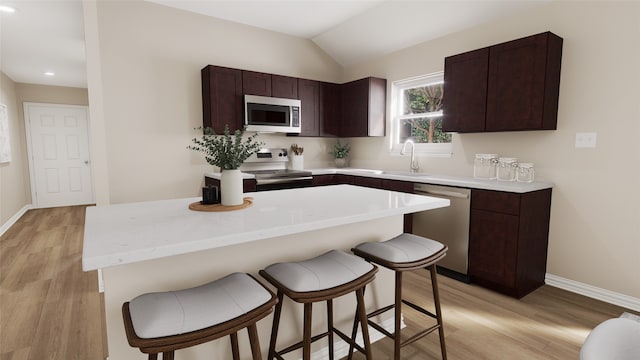 kitchen with sink, a kitchen breakfast bar, light hardwood / wood-style floors, lofted ceiling, and appliances with stainless steel finishes