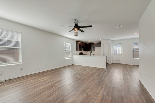 unfurnished living room with ceiling fan, light wood-type flooring, and sink