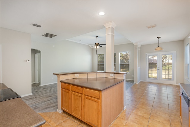 kitchen featuring french doors, decorative light fixtures, a center island, light tile patterned floors, and decorative columns