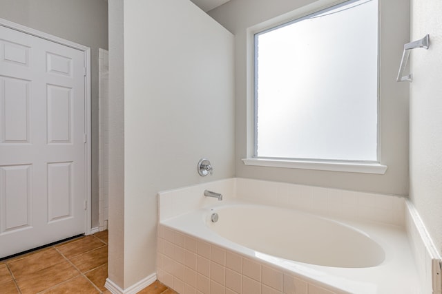 bathroom with a relaxing tiled tub and tile patterned floors