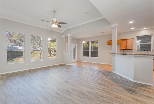 unfurnished living room featuring crown molding, ceiling fan, light hardwood / wood-style floors, and ornate columns