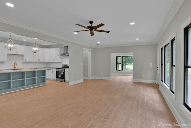 unfurnished living room featuring sink, light hardwood / wood-style flooring, ceiling fan with notable chandelier, and ornamental molding