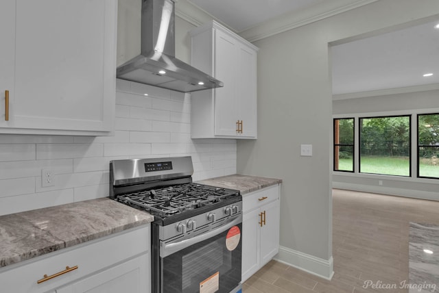 kitchen with wall chimney exhaust hood, stainless steel range with gas cooktop, light stone counters, light hardwood / wood-style floors, and white cabinets