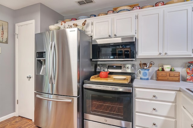 kitchen with stainless steel appliances, white cabinets, and light hardwood / wood-style floors