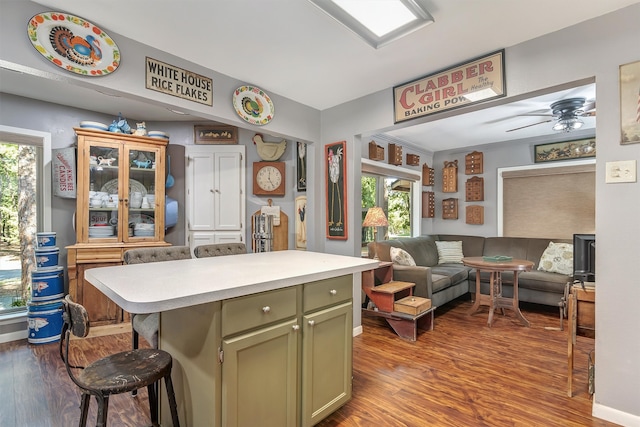 kitchen featuring light hardwood / wood-style flooring, ceiling fan, a breakfast bar area, and green cabinetry