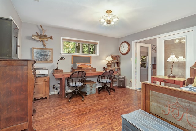 home office with dark wood-type flooring and a chandelier