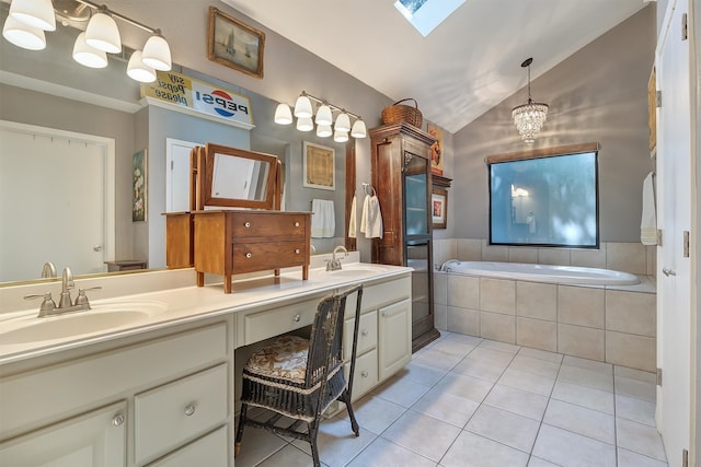 bathroom with tile patterned floors, a chandelier, vanity, vaulted ceiling with skylight, and tiled bath