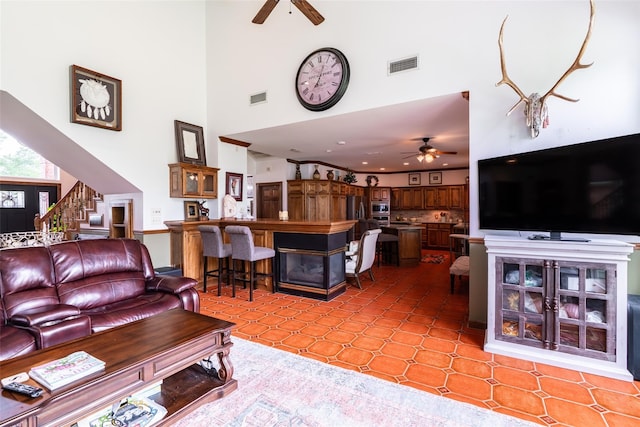 living room featuring ceiling fan, a towering ceiling, and light tile patterned floors