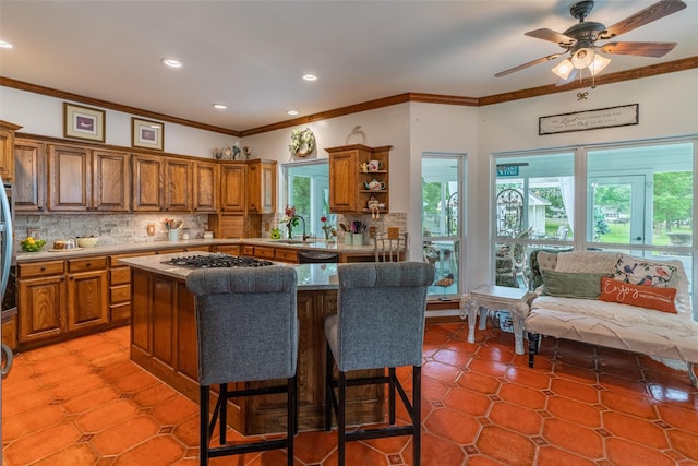 kitchen featuring ceiling fan, stainless steel gas cooktop, a kitchen bar, decorative backsplash, and a kitchen island