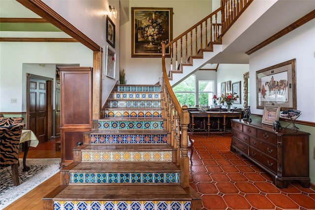 staircase with ornamental molding and a towering ceiling