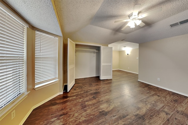 unfurnished bedroom featuring ceiling fan, dark hardwood / wood-style floors, a textured ceiling, vaulted ceiling, and a closet