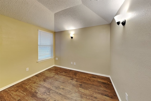 spare room featuring hardwood / wood-style floors, lofted ceiling, and a textured ceiling