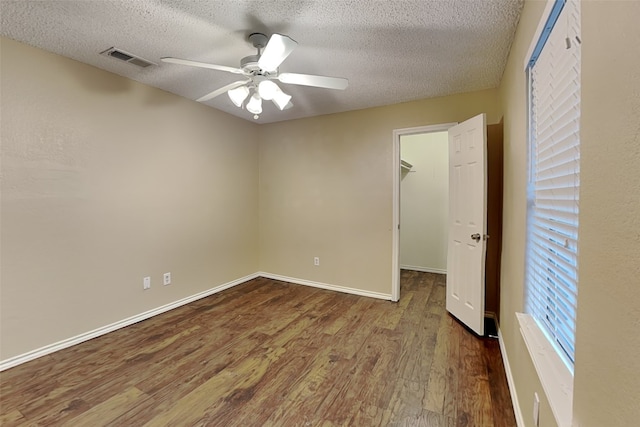 empty room with ceiling fan, wood-type flooring, and a textured ceiling