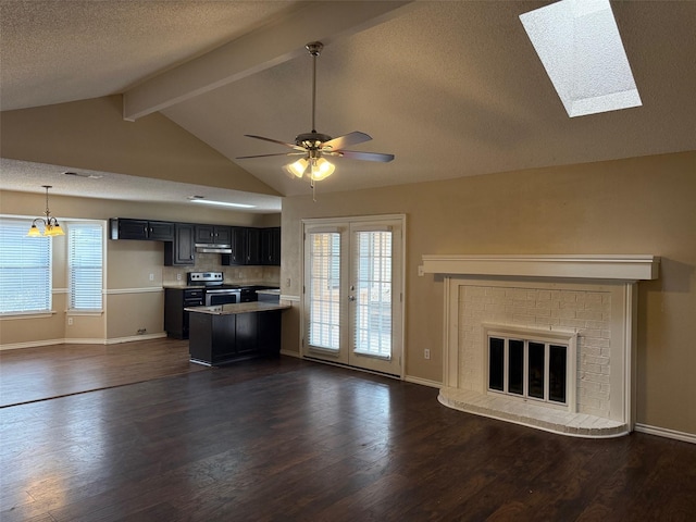 unfurnished living room with lofted ceiling with skylight, dark wood-type flooring, ceiling fan, a textured ceiling, and a fireplace