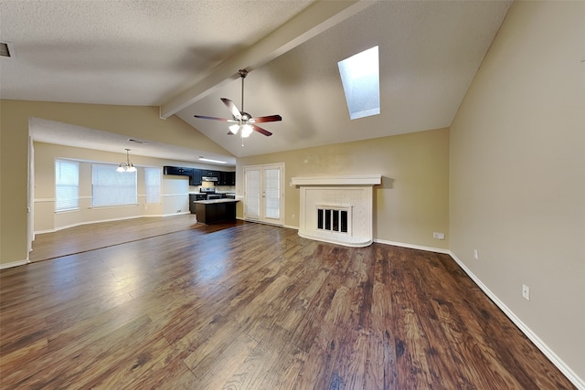 unfurnished living room with ceiling fan, dark hardwood / wood-style flooring, lofted ceiling with skylight, and a textured ceiling