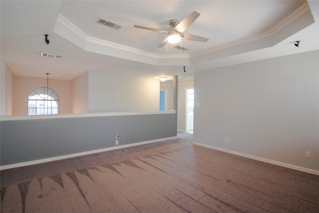 carpeted empty room featuring a raised ceiling, ornamental molding, and ceiling fan