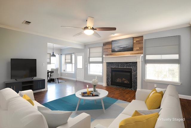 living room featuring crown molding, dark wood-type flooring, ceiling fan, and a fireplace