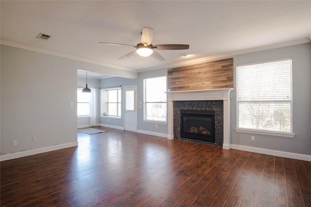 unfurnished living room with a fireplace, crown molding, dark wood-type flooring, and ceiling fan