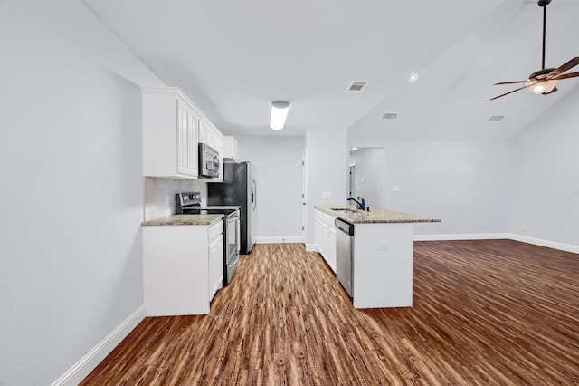 kitchen featuring white cabinets, wood-type flooring, stainless steel appliances, and light stone counters