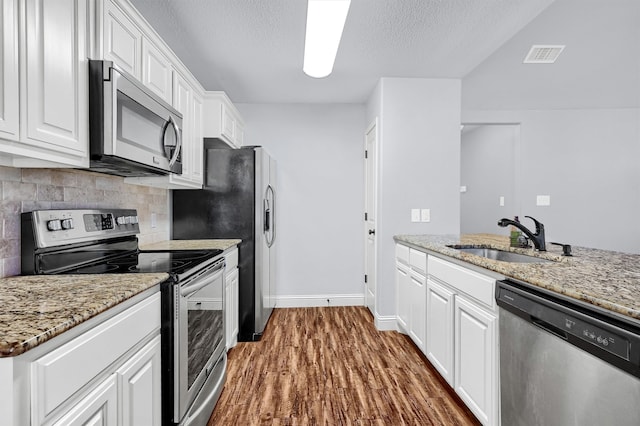 kitchen with white cabinetry, sink, dark wood-type flooring, light stone counters, and appliances with stainless steel finishes