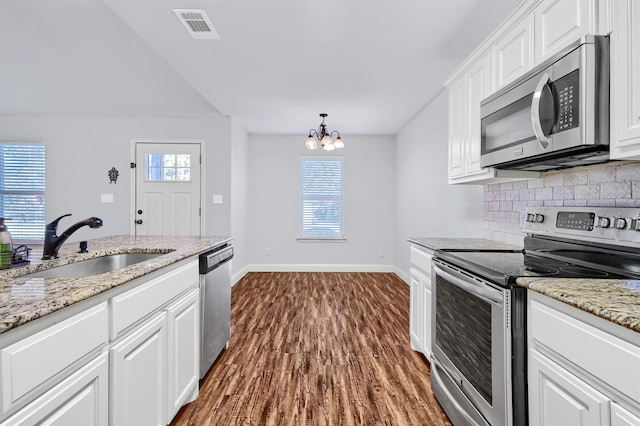 kitchen featuring dark wood-type flooring, white cabinets, sink, appliances with stainless steel finishes, and a chandelier