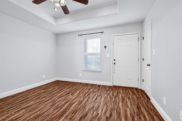 entrance foyer with a raised ceiling, ceiling fan, and dark hardwood / wood-style floors