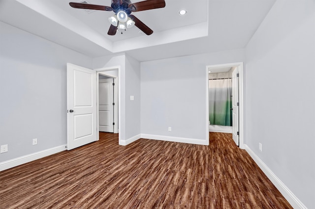 unfurnished bedroom with a raised ceiling, ceiling fan, and dark hardwood / wood-style flooring