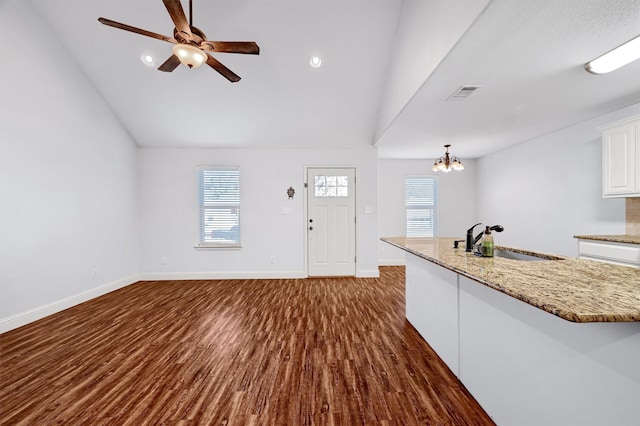 interior space featuring ceiling fan with notable chandelier, lofted ceiling, sink, and dark wood-type flooring