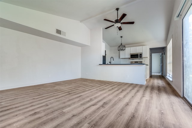 unfurnished living room featuring ceiling fan, light wood-type flooring, sink, and high vaulted ceiling