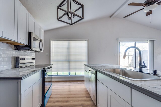 kitchen with sink, vaulted ceiling with beams, light hardwood / wood-style floors, white cabinetry, and stainless steel appliances