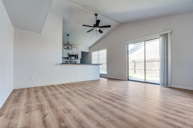 unfurnished living room with vaulted ceiling with beams, ceiling fan with notable chandelier, and light hardwood / wood-style flooring