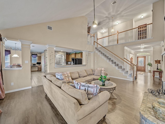 living area featuring decorative columns, visible vents, baseboards, stairway, and wood finished floors