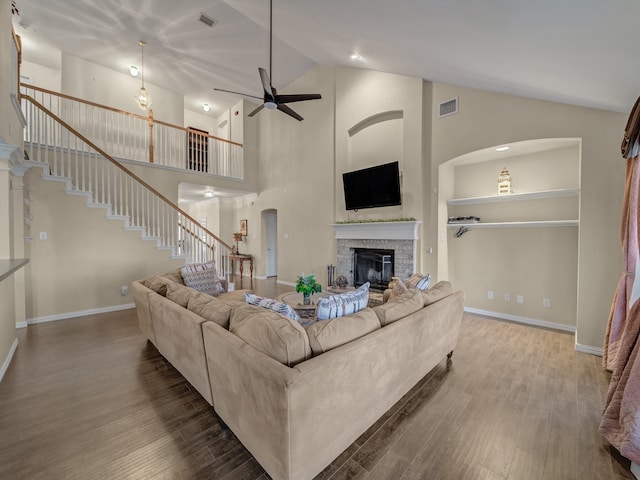 living room with built in shelves, ceiling fan, hardwood / wood-style flooring, high vaulted ceiling, and a fireplace