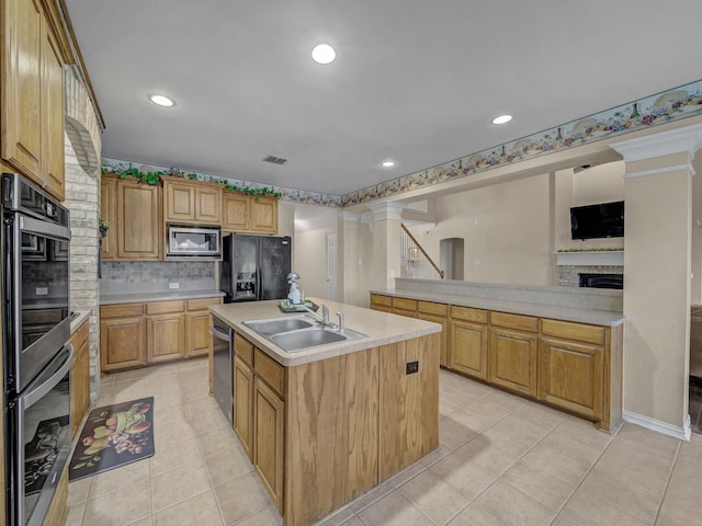 kitchen with sink, decorative backsplash, a center island with sink, light tile patterned floors, and appliances with stainless steel finishes