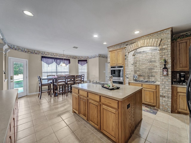 kitchen with a center island, pendant lighting, light countertops, double oven, and light tile patterned flooring