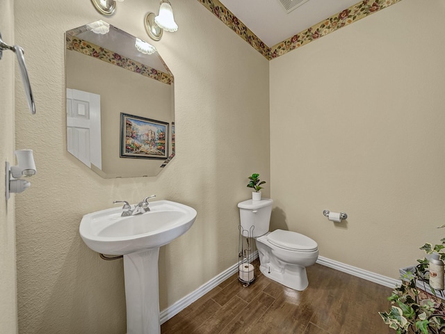 bathroom with toilet, baseboards, and wood finished floors