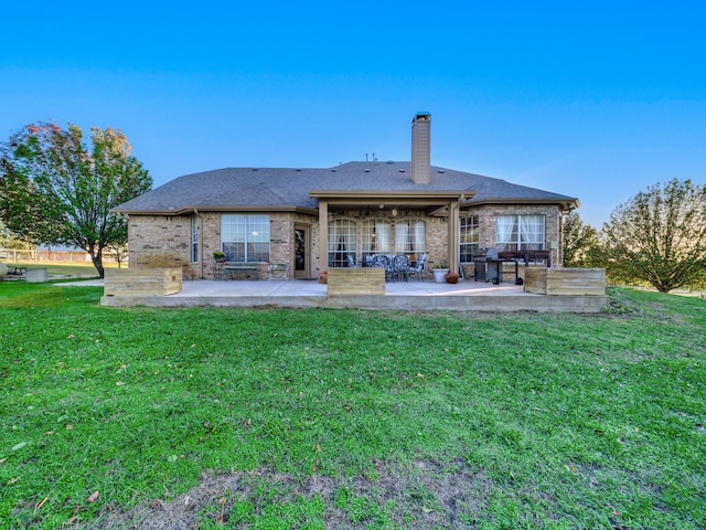 back of house with a patio area and a lawn