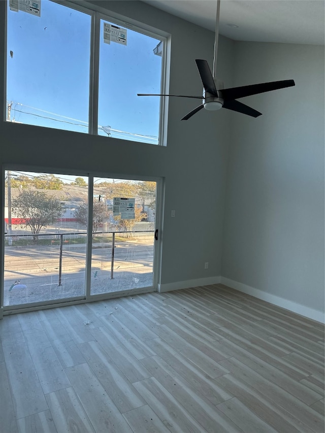 unfurnished living room featuring a towering ceiling, hardwood / wood-style floors, and ceiling fan