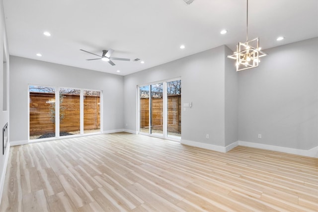 unfurnished living room featuring ceiling fan with notable chandelier and light wood-type flooring