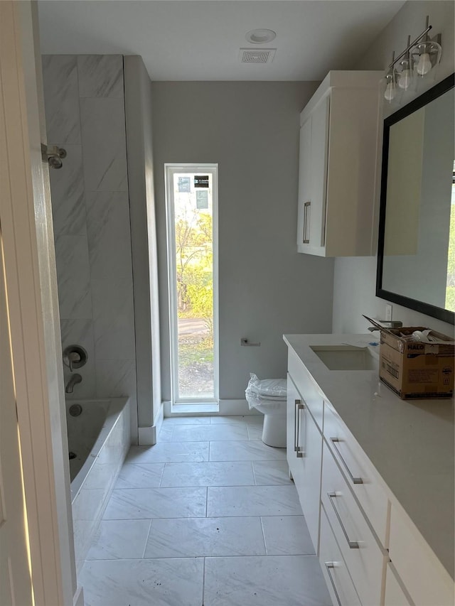 full bathroom with vanity, tiled shower / bath combo, and toilet