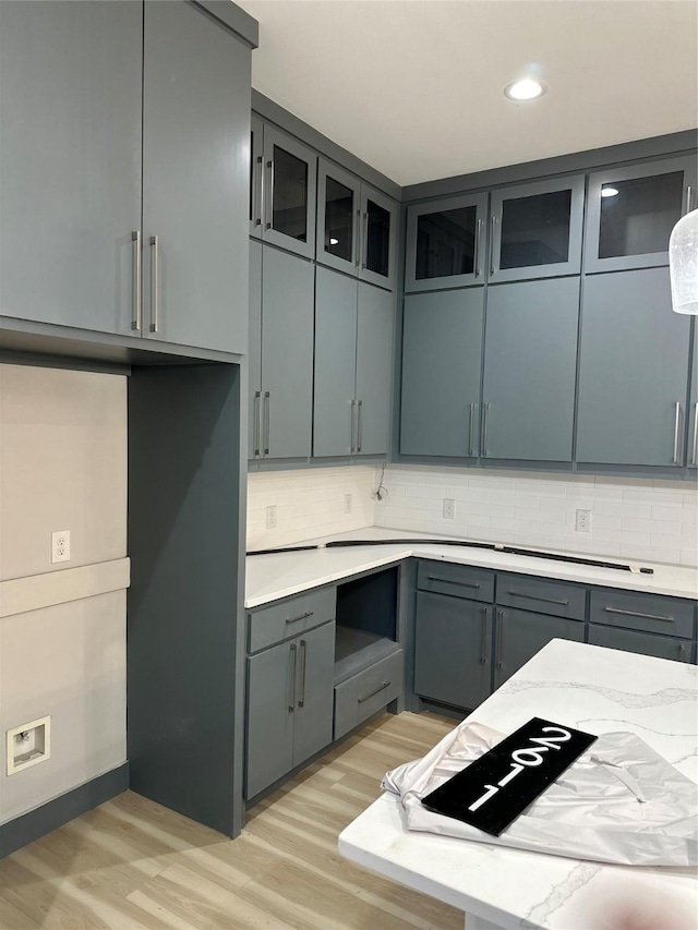 kitchen with tasteful backsplash, light stone counters, and light wood-type flooring