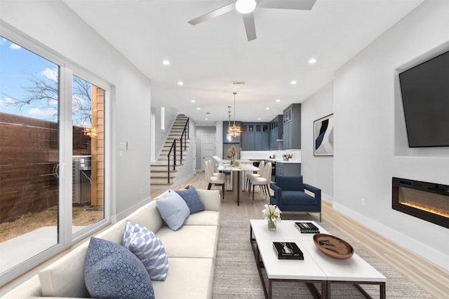 living room featuring hardwood / wood-style floors and ceiling fan with notable chandelier