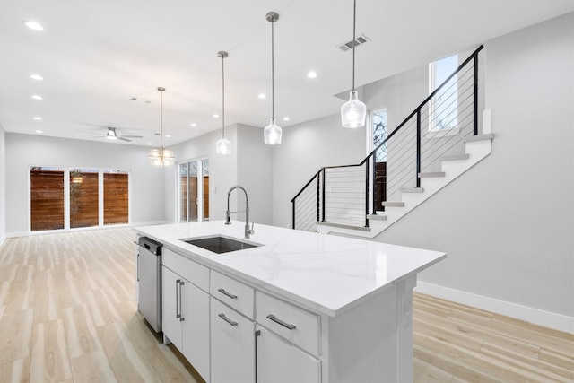 kitchen with sink, stainless steel dishwasher, an island with sink, pendant lighting, and white cabinets