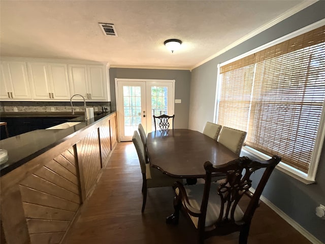 dining room with dark hardwood / wood-style flooring, ornamental molding, and french doors