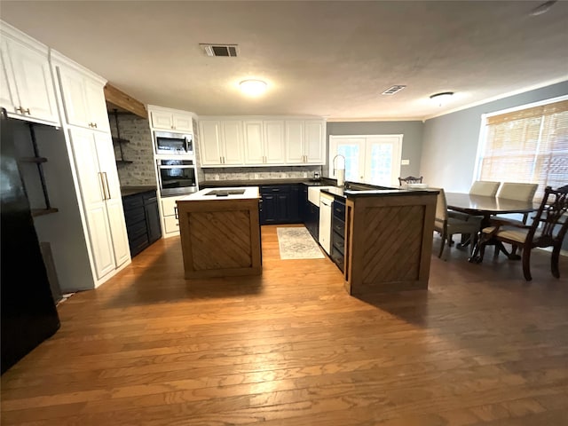 kitchen featuring backsplash, appliances with stainless steel finishes, a kitchen island, and white cabinets