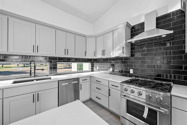 kitchen with backsplash, wall chimney exhaust hood, stainless steel appliances, vaulted ceiling, and sink