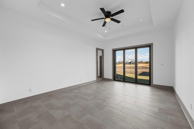 empty room with a raised ceiling and ceiling fan